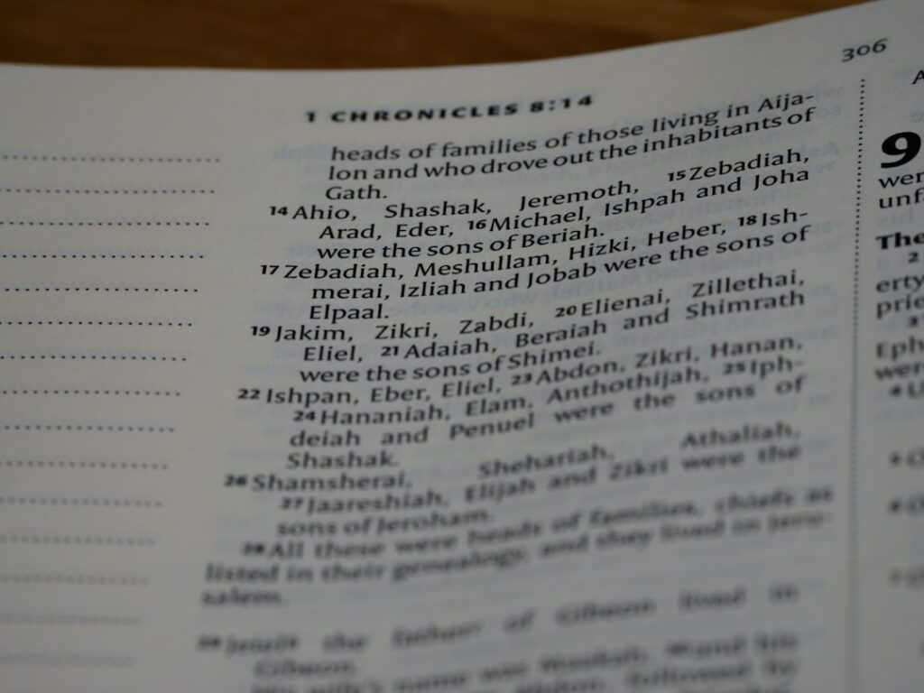 A close-up of a printed Hebrew menu with recognizable food words and hands pointing at the dishes.