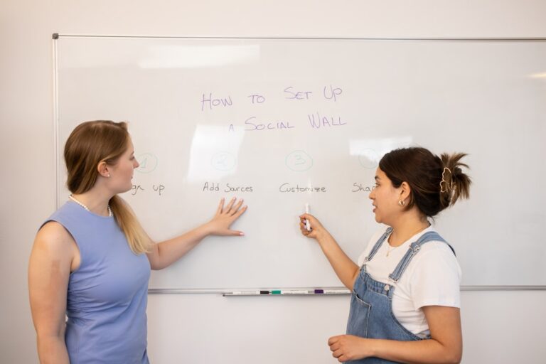 Two people engaged in conversation while reviewing Hebrew notes at a public library table.