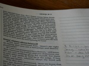 Beginner students study Hebrew letters and grammar in notebooks around a table.