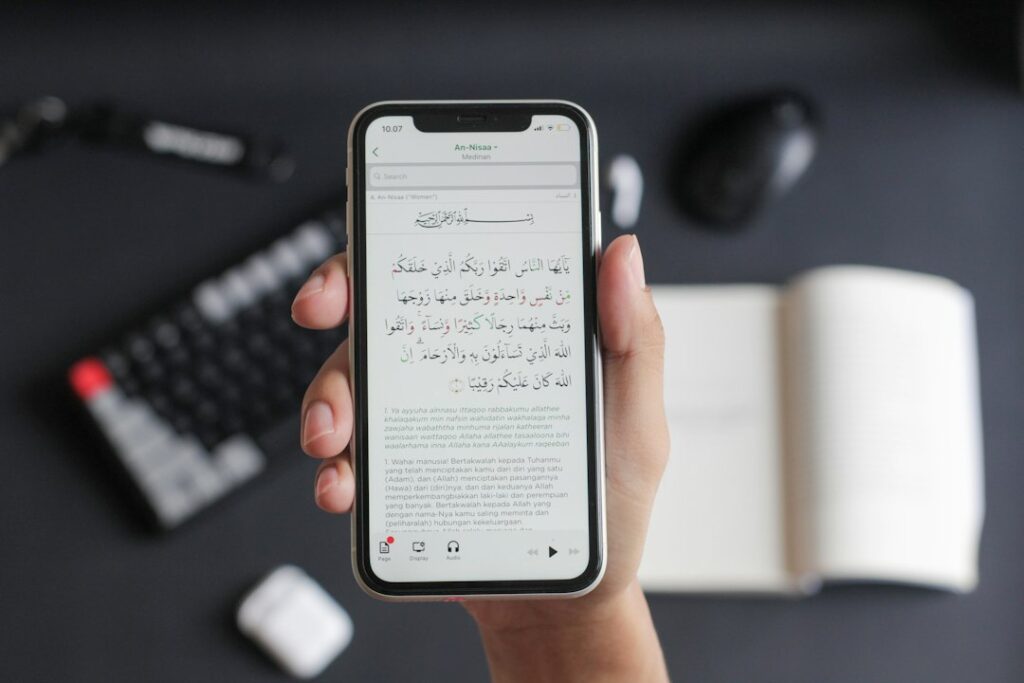 A person typing on a smartphone showing both Hebrew and English characters on the screen.