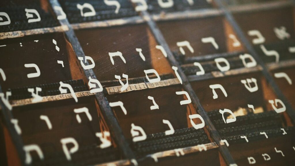 Adult learner practicing Hebrew letters in a notebook beside flashcards and a cup of tea.