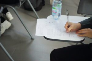 Student at a desk reviewing Hebrew text, vocabulary cards, and handwritten practice answers.