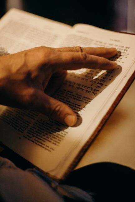 Adult and child read a Hebrew prayer book together at a table with handwritten vocabulary notes.