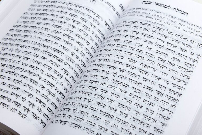 A learner reads Hebrew letters aloud beside a notebook, pencil, and open language workbook at a home desk.