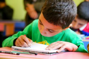 A learner studies Hebrew vocabulary with handwritten flashcards, a notebook, and labeled household objects.