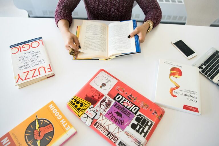 A person compares Hebrew and English text in two open books beside handwritten notes.