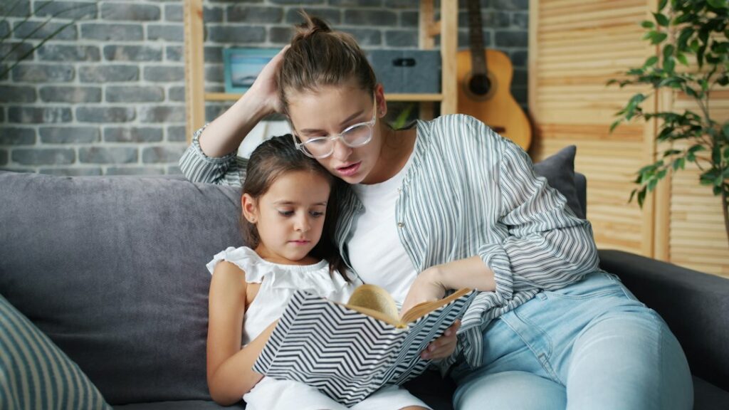 Adult and child reading a Hebrew book together at a kitchen table with notebooks and handwritten vocabulary nearby