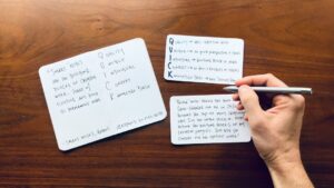 Adult and child reading Hebrew together at a kitchen table with notebooks and flashcards.