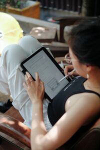 Adult learner practices Hebrew letters and listens to an audio lesson on a tablet at a kitchen table.