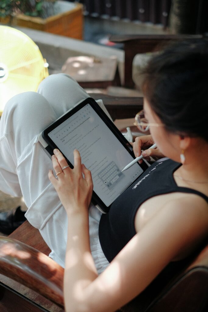 Adult learner practices Hebrew letters and listens to an audio lesson on a tablet at a kitchen table.