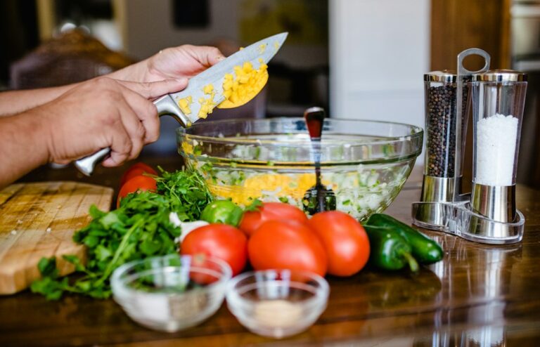 Family members prepare Israeli salad in a kitchen with vegetables, bowls, and Hebrew vocabulary cards.