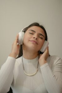 A learner listens to Hebrew audio with headphones beside an open notebook and written vocabulary.