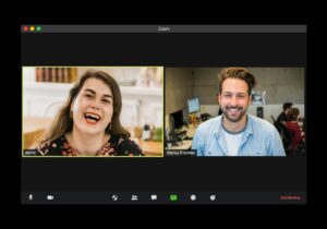 Two adults practice Hebrew through a video call with notebooks and Hebrew vocabulary cards nearby.