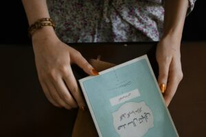 Learner practicing Hebrew letters in a notebook beside alphabet cards and a pencil.
