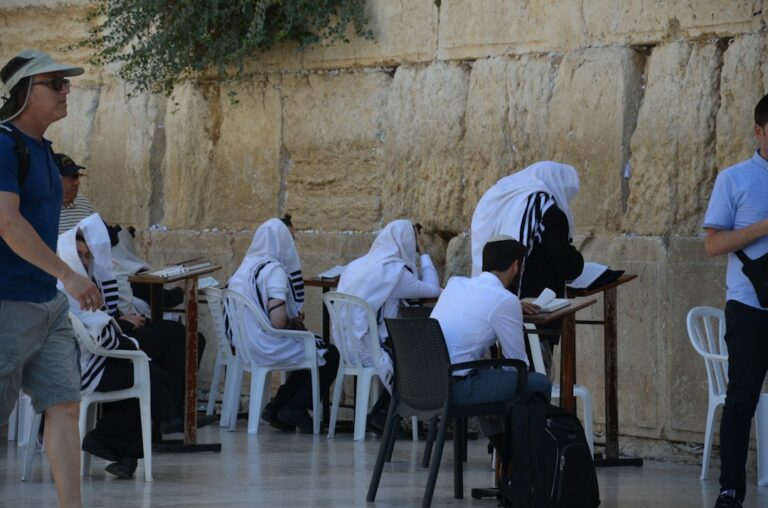Two adults practice Hebrew emotion phrases at a table with notebooks and handwritten vocabulary cards.