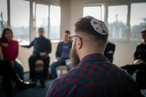Two adults practice Hebrew at a table with notebooks, handwritten phrases, and cups of tea.