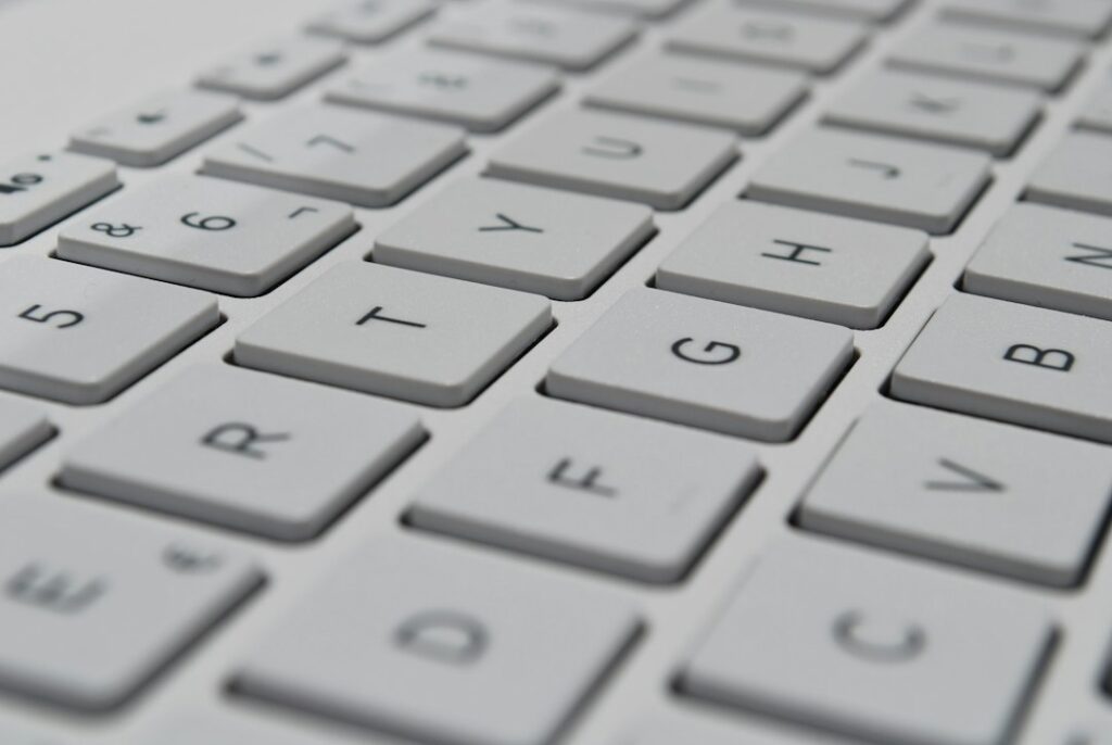 A learner types Hebrew on a laptop beside a phone displaying a right-to-left message.