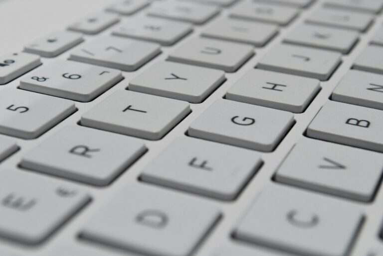 A learner types Hebrew on a laptop beside a phone displaying a right-to-left message.