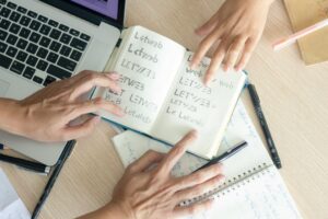 Adult and child practice Hebrew words together at a kitchen table with notebooks and Hebrew letter cards.