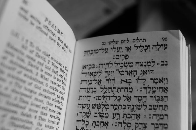 A student compares Hebrew words and English translations in a notebook beside an open Hebrew textbook.