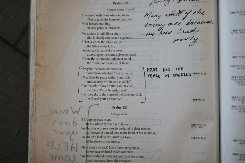 Two adults practice Hebrew greetings from a notebook at a kitchen table.
