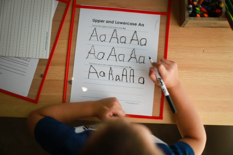 Student practicing right-to-left Hebrew letters on lined paper with a pencil and alphabet reference sheet.