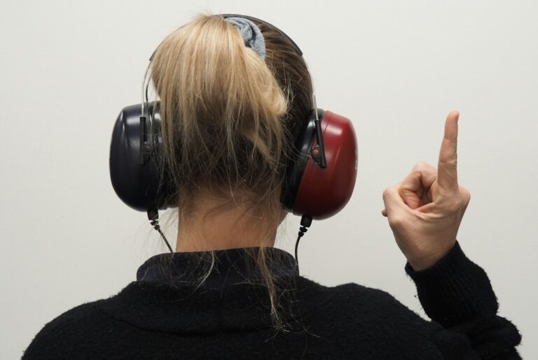 A learner listens to Hebrew audio while following a printed transcript at a home desk.
