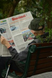 Learner reading a Hebrew news article beside a notebook and listening to a short broadcast on a laptop.