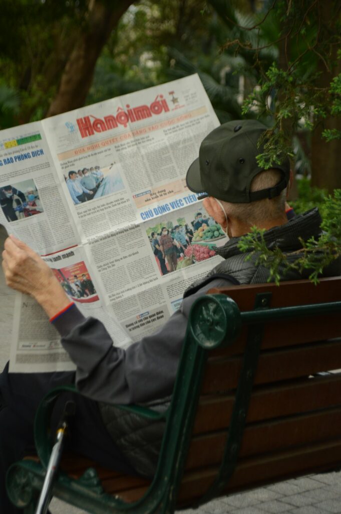 Learner reading a Hebrew news article beside a notebook and listening to a short broadcast on a laptop.