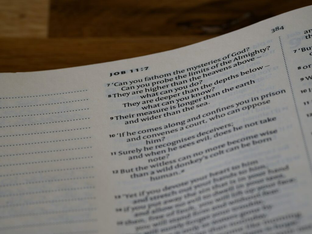 A student studies Hebrew prepositions from a workbook beside handwritten examples and a Hebrew alphabet chart.