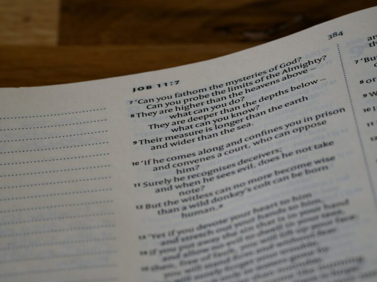 A student studies Hebrew prepositions from a workbook beside handwritten examples and a Hebrew alphabet chart.