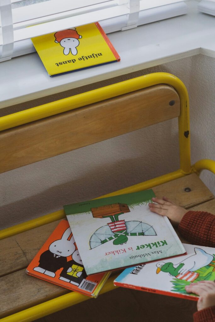 Child and parent read a colorful Hebrew picture book together at a table with pencils and illustrated pages.