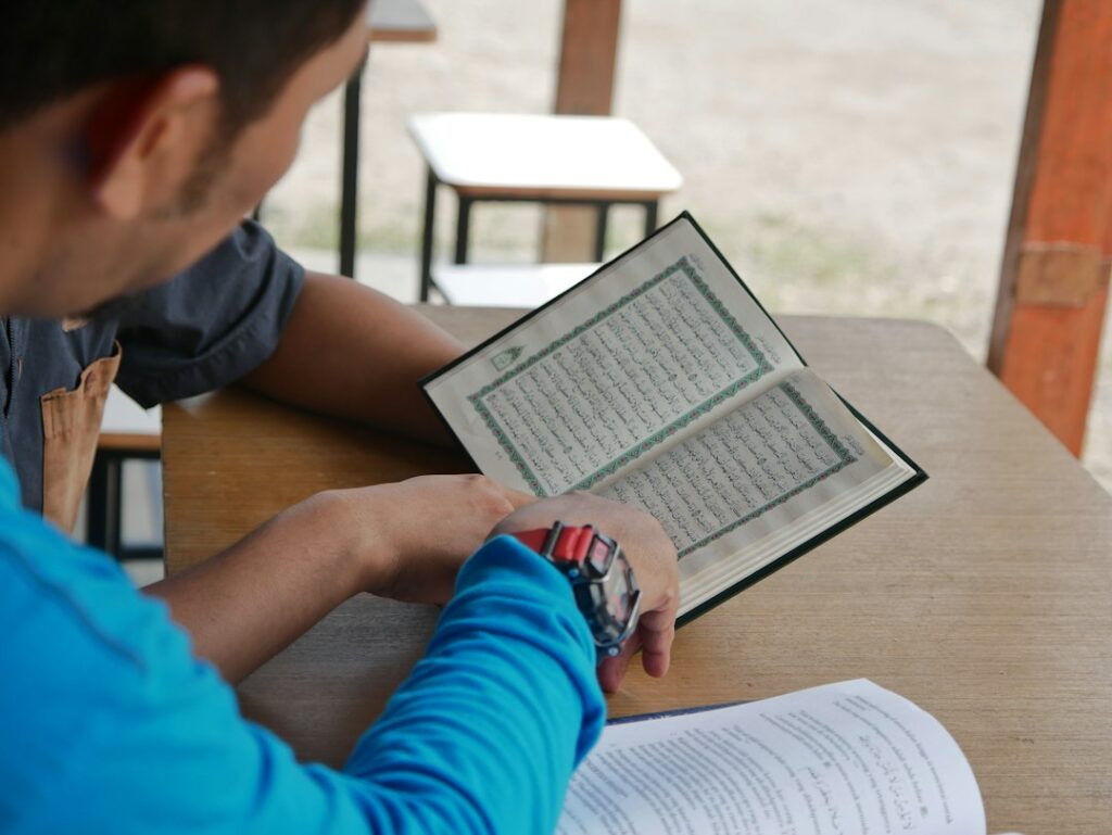 A learner reads a Hebrew text while marking words and discussing sentence meaning with a teacher.