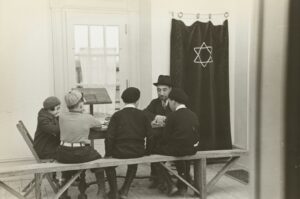Students read Hebrew books together at a table with notebooks, vocabulary cards, and open language texts.