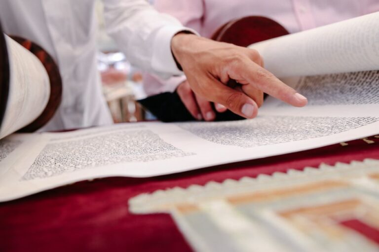 Children read Hebrew books and write letters at desks in a bright elementary classroom.