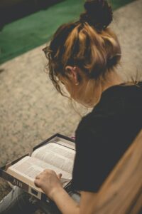 Adult learner reads Hebrew aloud while practicing pronunciation with notes and a recording device on a table.