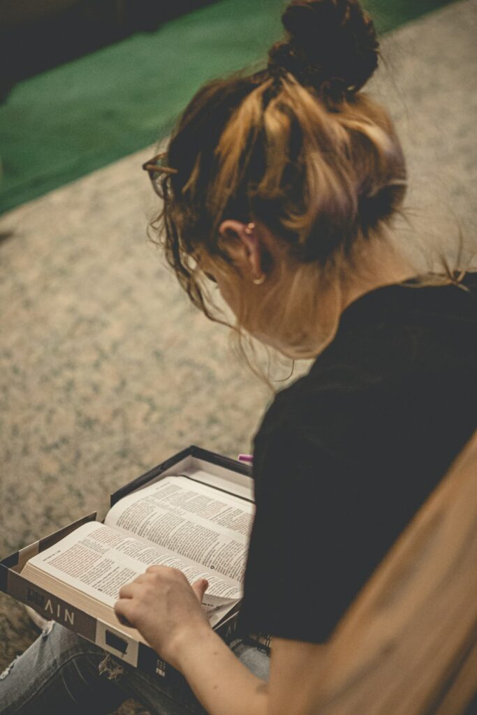 Adult learner reads Hebrew aloud while practicing pronunciation with notes and a recording device on a table.