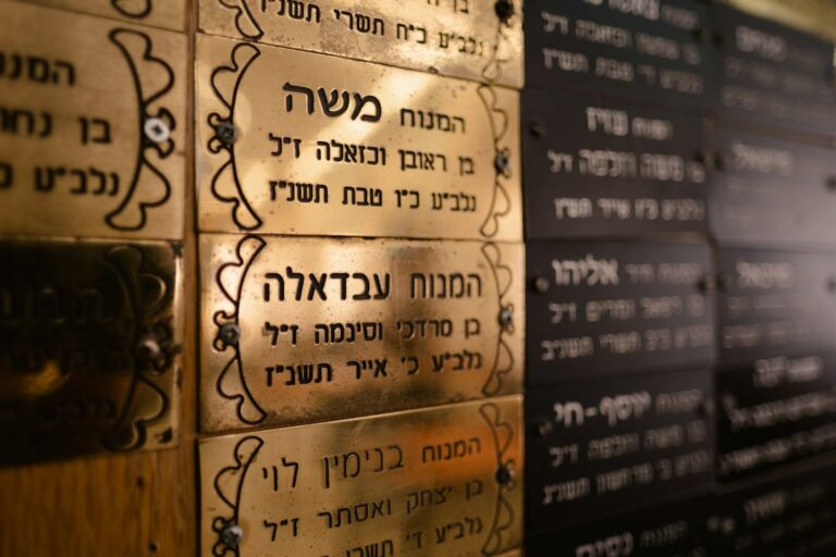 Adult learners practice Hebrew letters and conversation around a table with notebooks and printed text.