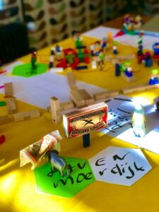 Children and an adult play Hebrew word cards at a table with notebooks, pencils, and picture cards.