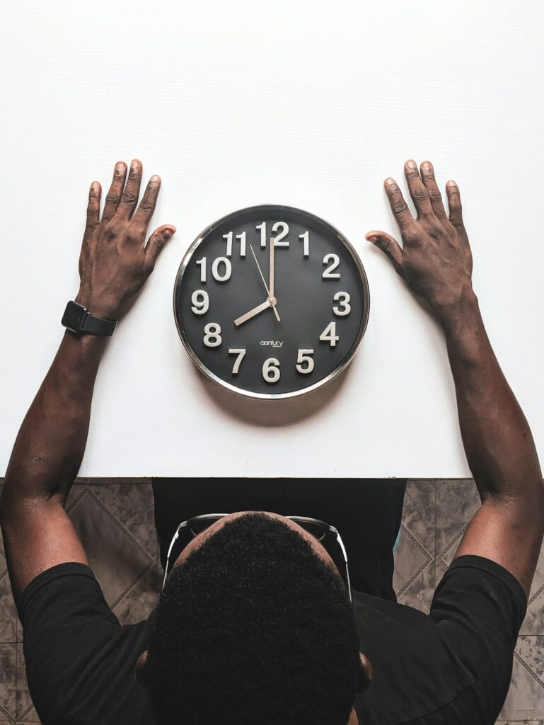 A learner studies Hebrew numbers beside an analog clock and handwritten time expressions.