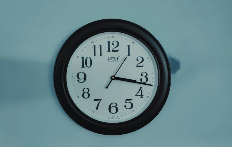 A learner studies Hebrew time expressions beside a clock, notebook, and handwritten Hebrew numbers.