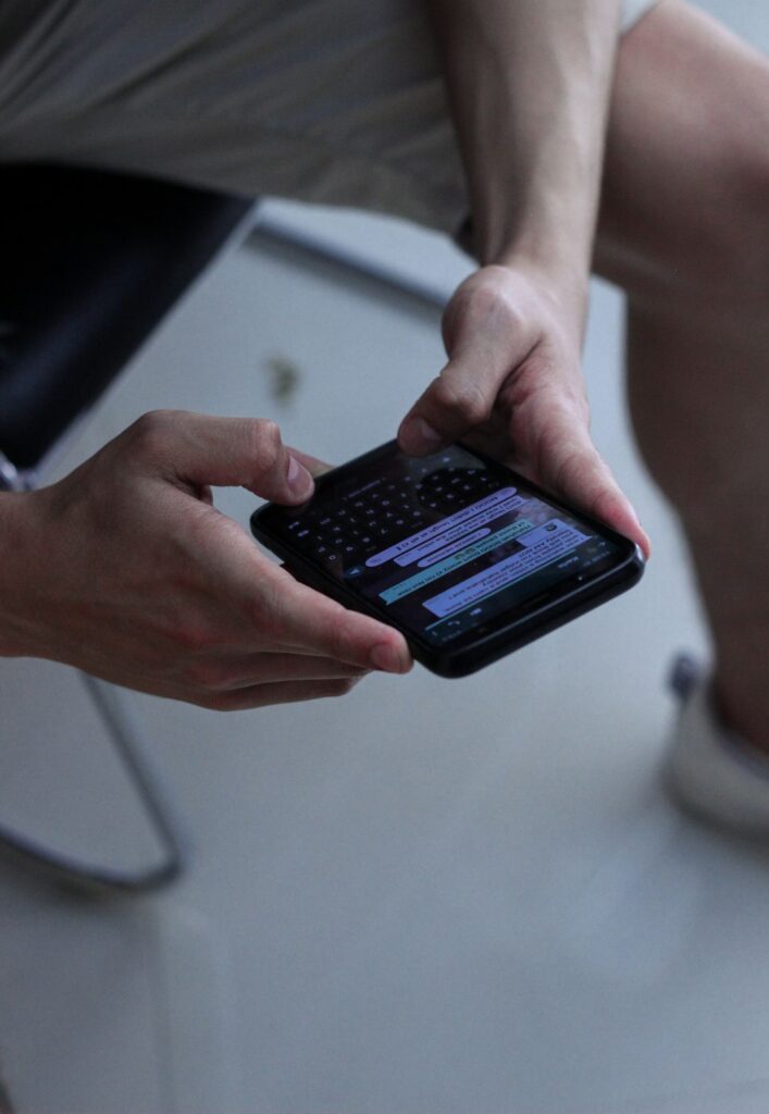 Adult and child reading Hebrew messages on a smartphone beside an open Hebrew notebook.