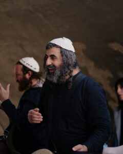Adult and child follow Hebrew lyrics on paper while listening to music at a kitchen table.