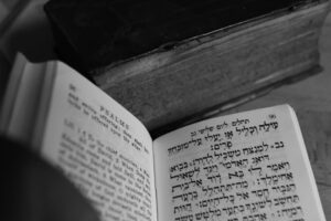 An adult and child compare Hebrew and English words in an open notebook at a kitchen table.